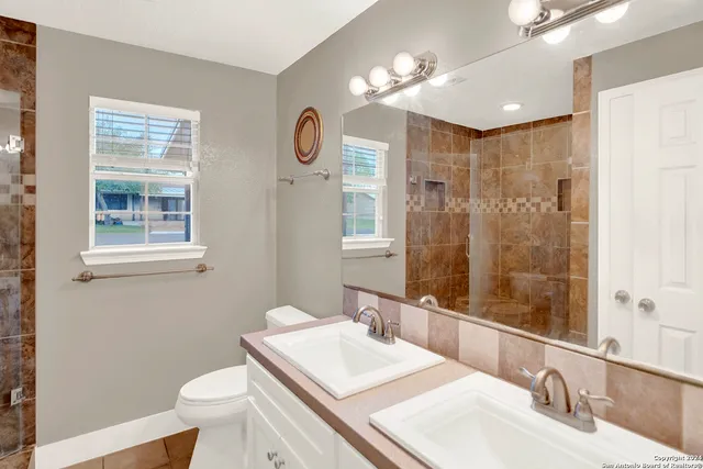 a bathroom with a sink a toilet a mirror and shower