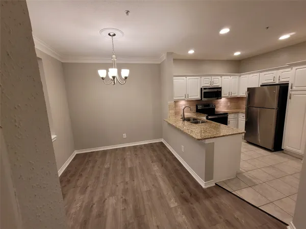 a kitchen with granite countertop stainless steel appliances a stove a refrigerator a sink a stove with wooden floor and cabinets