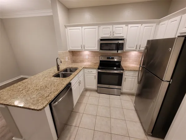a kitchen with granite countertop a refrigerator and a sink
