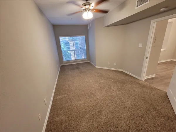 an empty room with windows and chandelier fan