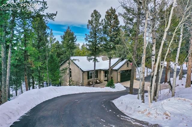 Asphalt driveway extends across the front and over to the detached garage area