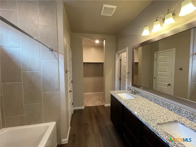a bathroom with a granite countertop sink a large mirror and a bathtub