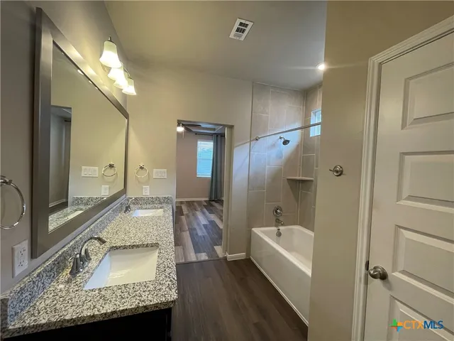 a bathroom with a granite countertop tub sink and mirror