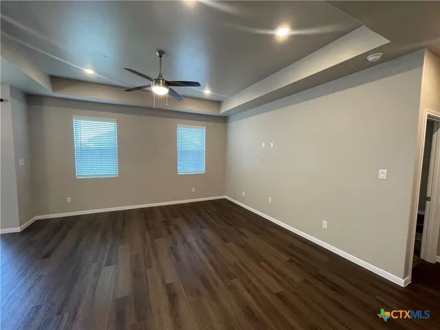 an empty room with wooden floor chandelier and windows