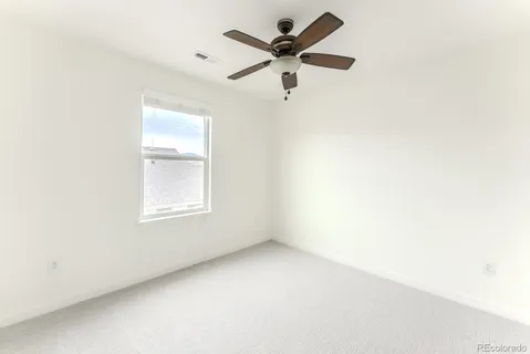 an empty room with a window and a fan