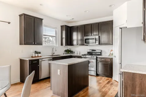 a kitchen with stainless steel appliances granite countertop a stove top oven a sink and dishwasher a refrigerator with wooden floor