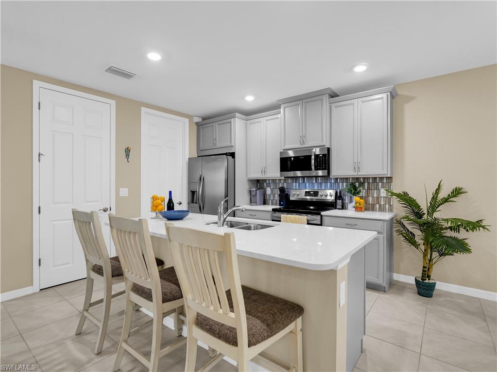 14695 Edgewater Circle Naples, FL 34114 - Photo 10 of 39 a kitchen with a dining table a microwave and refrigerator