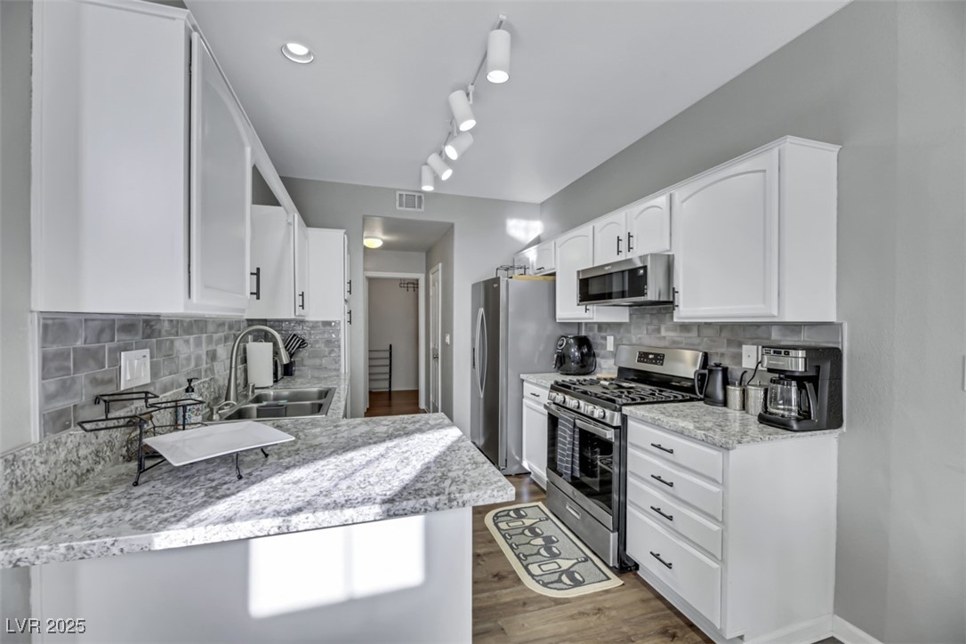 2907 Rio Sonora Court Henderson, NV 89074 - Photo 12 of 35 Kitchen featuring stainless steel appliances, white cabinetry, tasteful backsplash, and light stone countertops