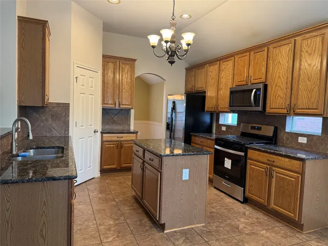 a kitchen with stainless steel appliances granite countertop a stove refrigerator and microwave