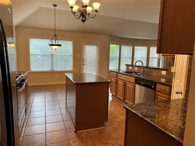 a kitchen with stainless steel appliances granite countertop a sink a stove counter space and cabinets