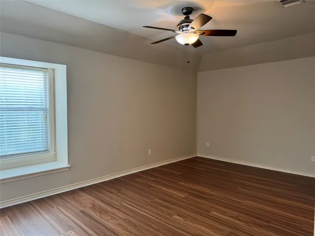 a view of a room with wooden floor and a ceiling fan