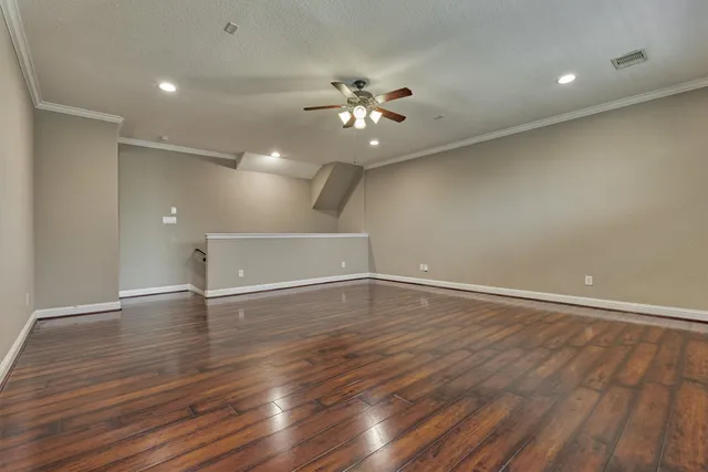 an empty room with wooden floor fan and windows