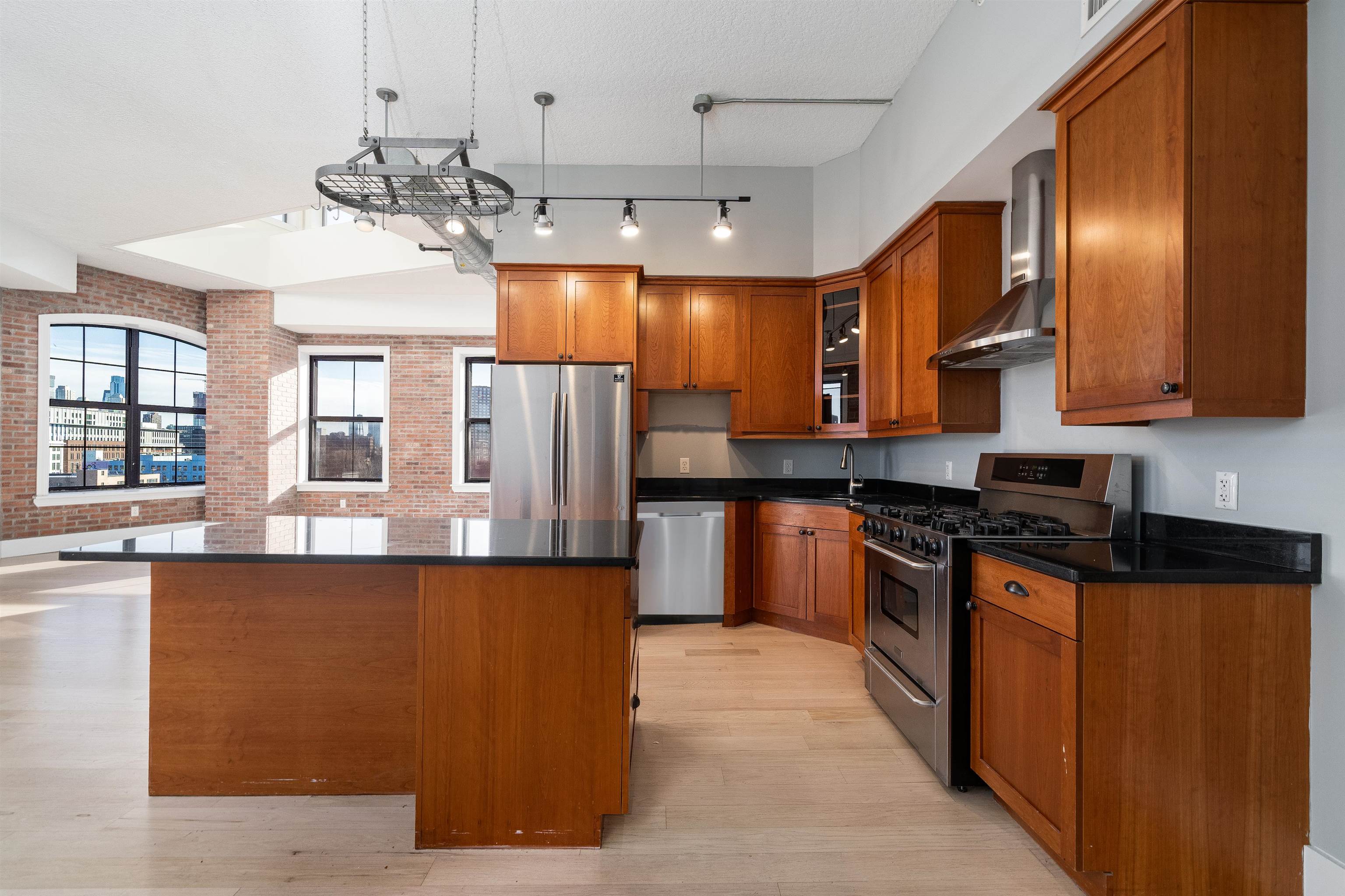 100 Paterson Plank Road, Unit 504 Jersey City, NJ 07307 - Photo 9 of 23 a large kitchen with stainless steel appliances granite countertop a stove a sink dishwasher and refrigerator with wooden floor