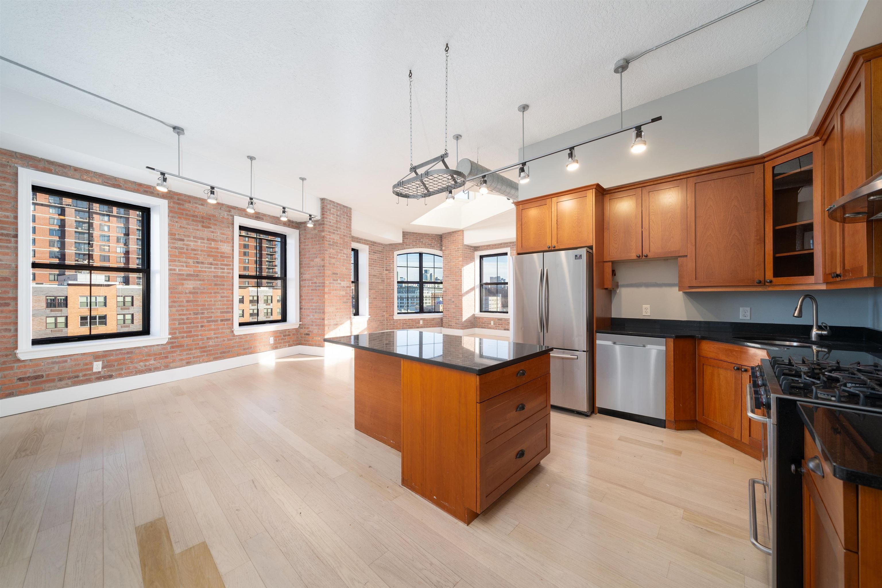 100 Paterson Plank Road, Unit 504 Jersey City, NJ 07307 - Photo 10 of 23 a large kitchen with kitchen island a large counter top space a sink a window and stainless steel appliances