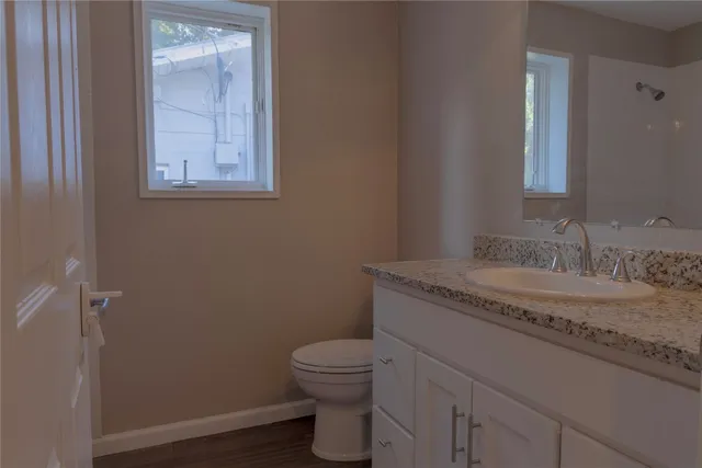 a bathroom with a granite countertop toilet a sink and a mirror
