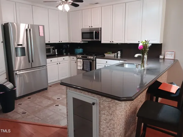 a kitchen with stainless steel appliances granite countertop a refrigerator a stove a sink a dining table and chairs