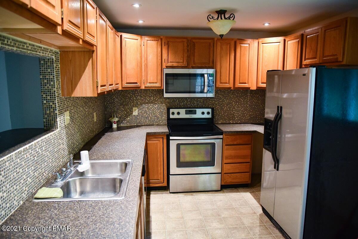 2202 Delaware Court East Bushkill, PA 18324 - Photo 5 of 18 a kitchen with stainless steel appliances granite countertop a refrigerator a stove and a sink with wooden floor
