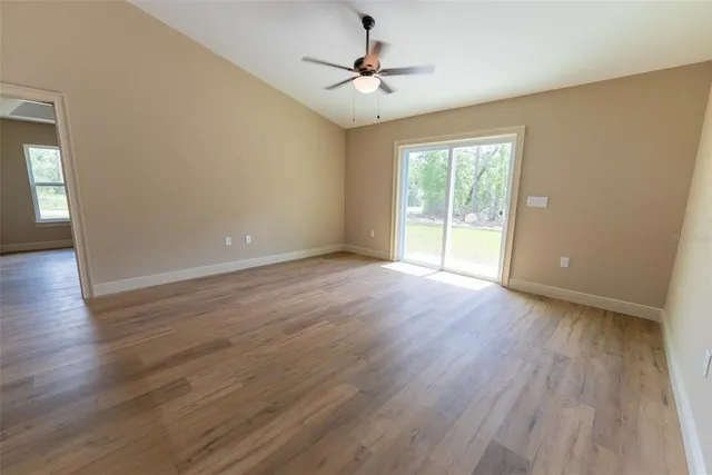 an empty room with wooden floor and a ceiling fan
