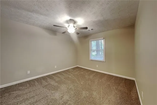 an empty room with a chandelier fan and windows