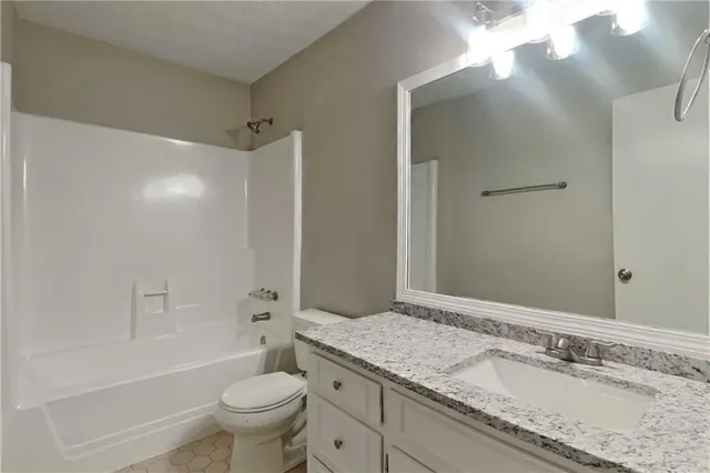 a bathroom with a granite countertop sink a toilet and a large mirror