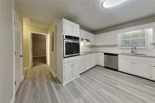 a kitchen with stainless steel appliances kitchen island granite countertop a sink cabinets and wooden floor
