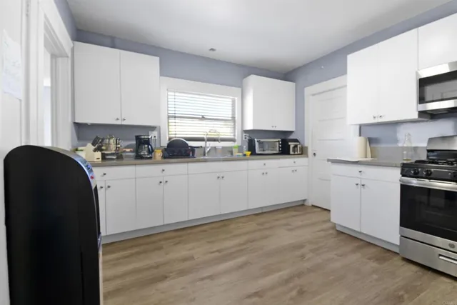 a kitchen with granite countertop a sink a stove refrigerator and cabinets