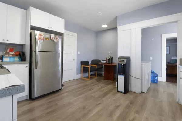 a view of a kitchen with refrigerator and wooden floor