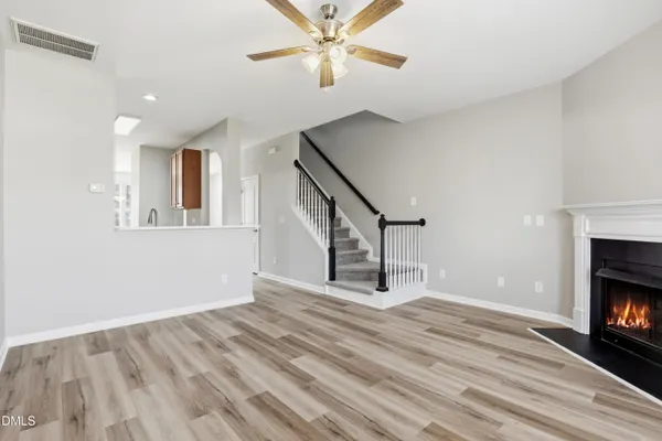 a view of an empty room with wooden floor fireplace and a window
