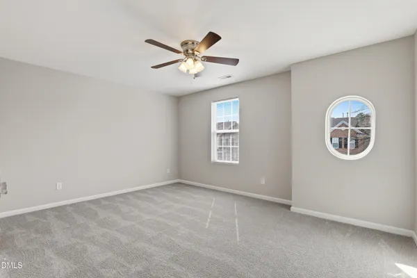 an empty room with windows and fan