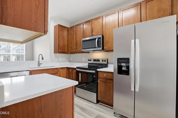 a kitchen with stainless steel appliances a refrigerator a sink a stove top oven a refrigerator and cabinets