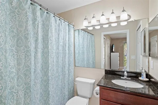 a bathroom with a granite countertop sink a toilet and a mirror