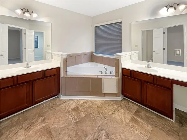 a spacious bathroom with a tub sink and mirror