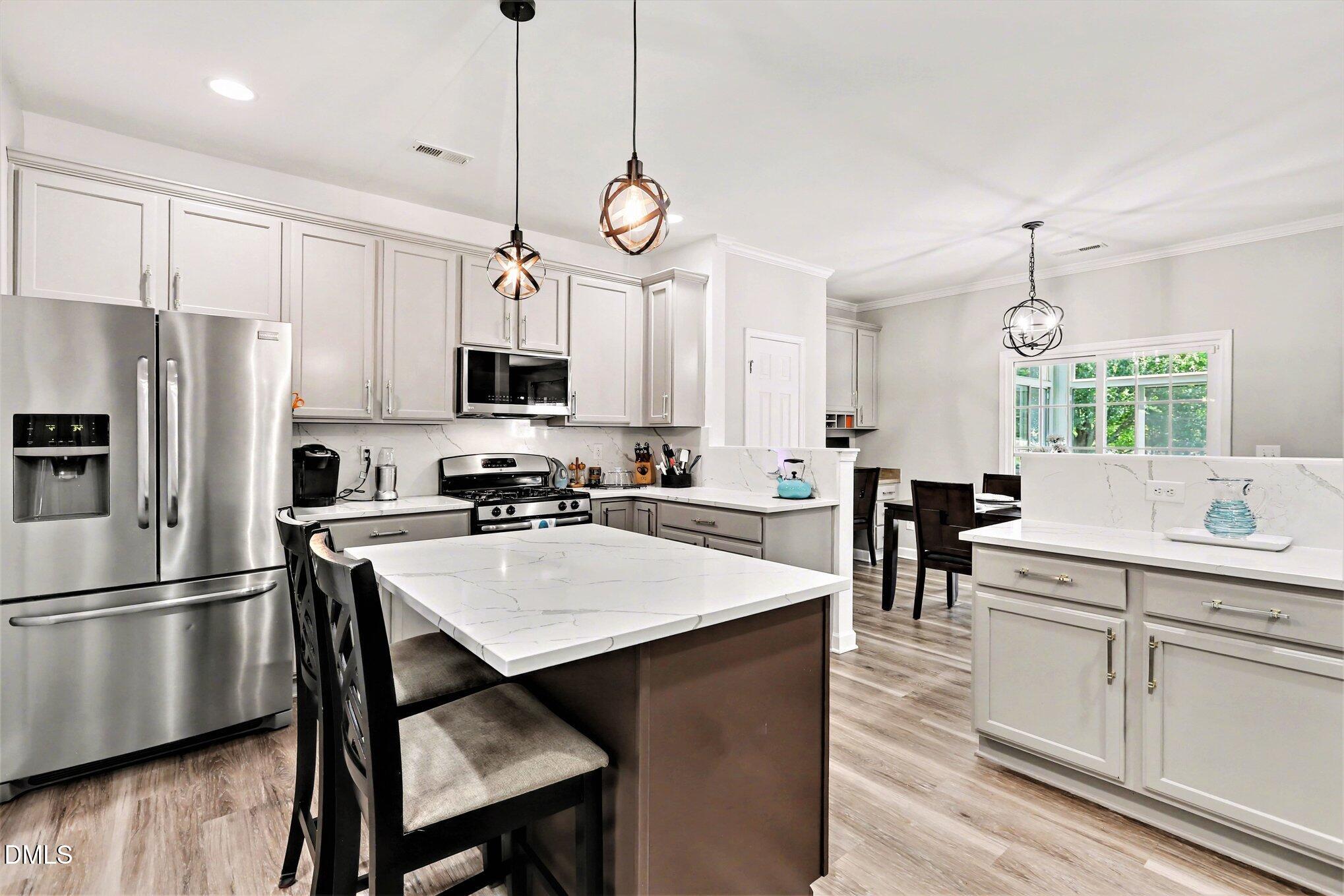 437 Field Glow Lane Apex, NC 27539 - Photo 17 of 48 a kitchen with stainless steel appliances a stove center island a refrigerator and cabinets