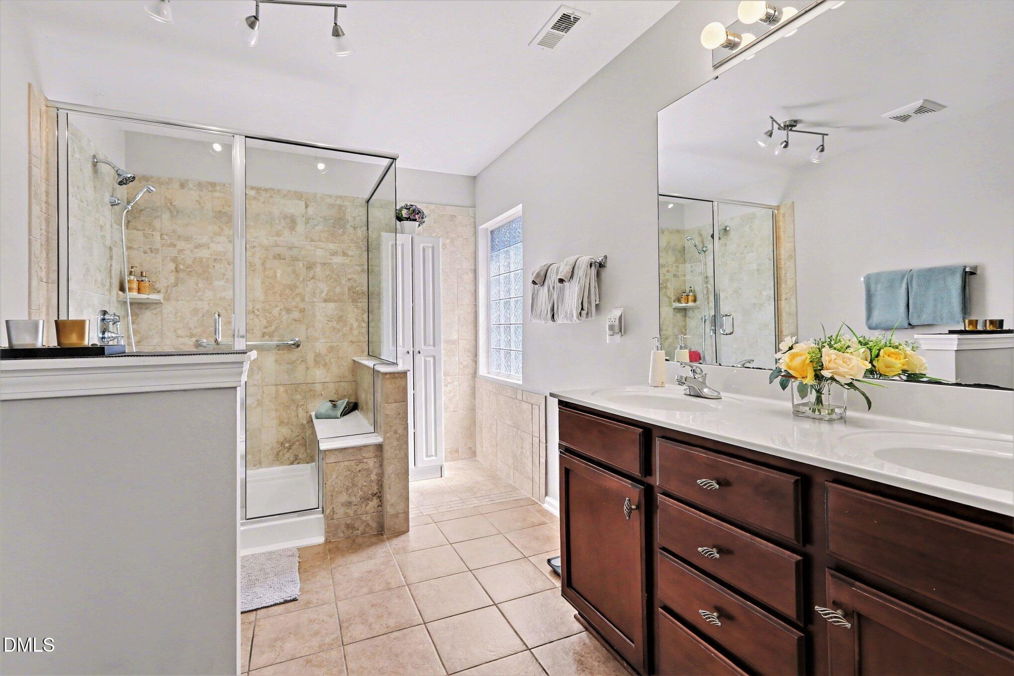 437 Field Glow Lane Apex, NC 27539 - Photo 29 of 48 a spacious bathroom with a granite countertop sink mirror and a bathtub