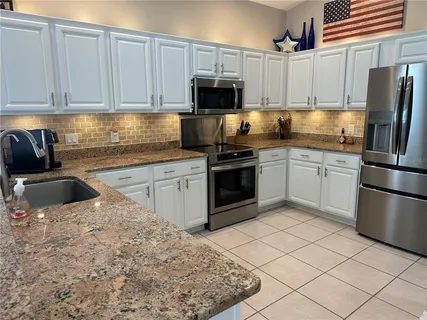 a kitchen with granite countertop a sink stove and refrigerator