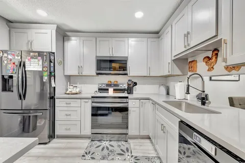 a kitchen with stainless steel appliances granite countertop a refrigerator stove a sink and dishwasher with wooden floor