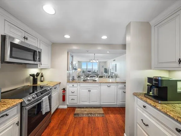 a kitchen with a sink dishwasher and white cabinets with wooden floor