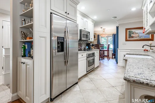 a kitchen with stainless steel appliances granite countertop a refrigerator a stove and a sink