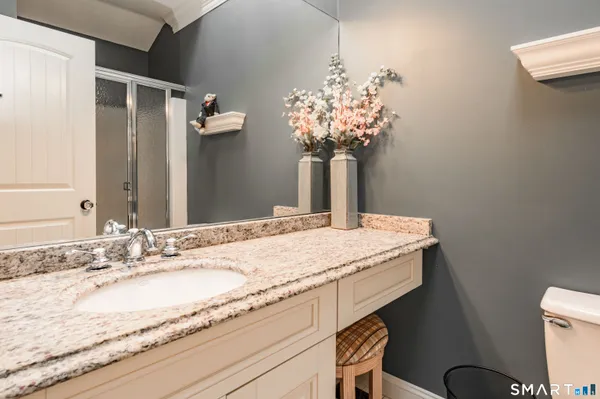 a bathroom with a granite countertop sink a toilet and a mirror