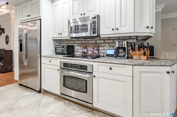 a kitchen with stainless steel appliances granite countertop a stove a refrigerator and a white cabinets
