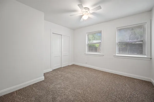 an empty room with windows and fan