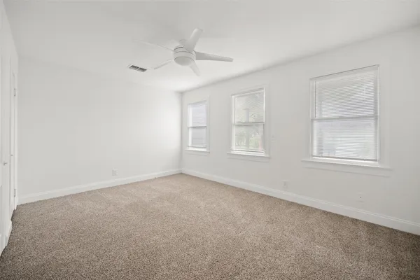 an empty room with windows and fan