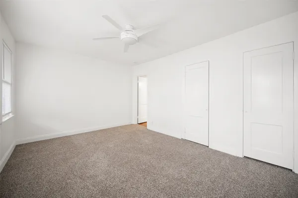 an empty room with a ceiling fan and a window