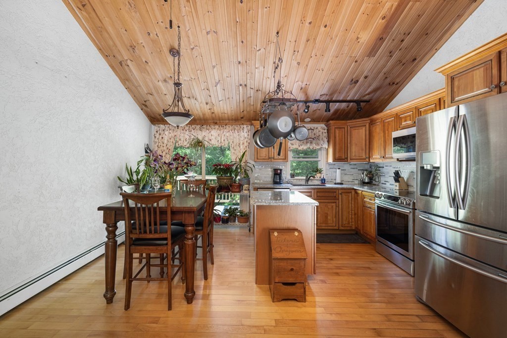 531 Fowler Road Northbridge, MA 01534 - Photo 7 of 41 a kitchen with stainless steel appliances granite countertop a refrigerator a stove a sink a dining table and chairs with wooden floor
