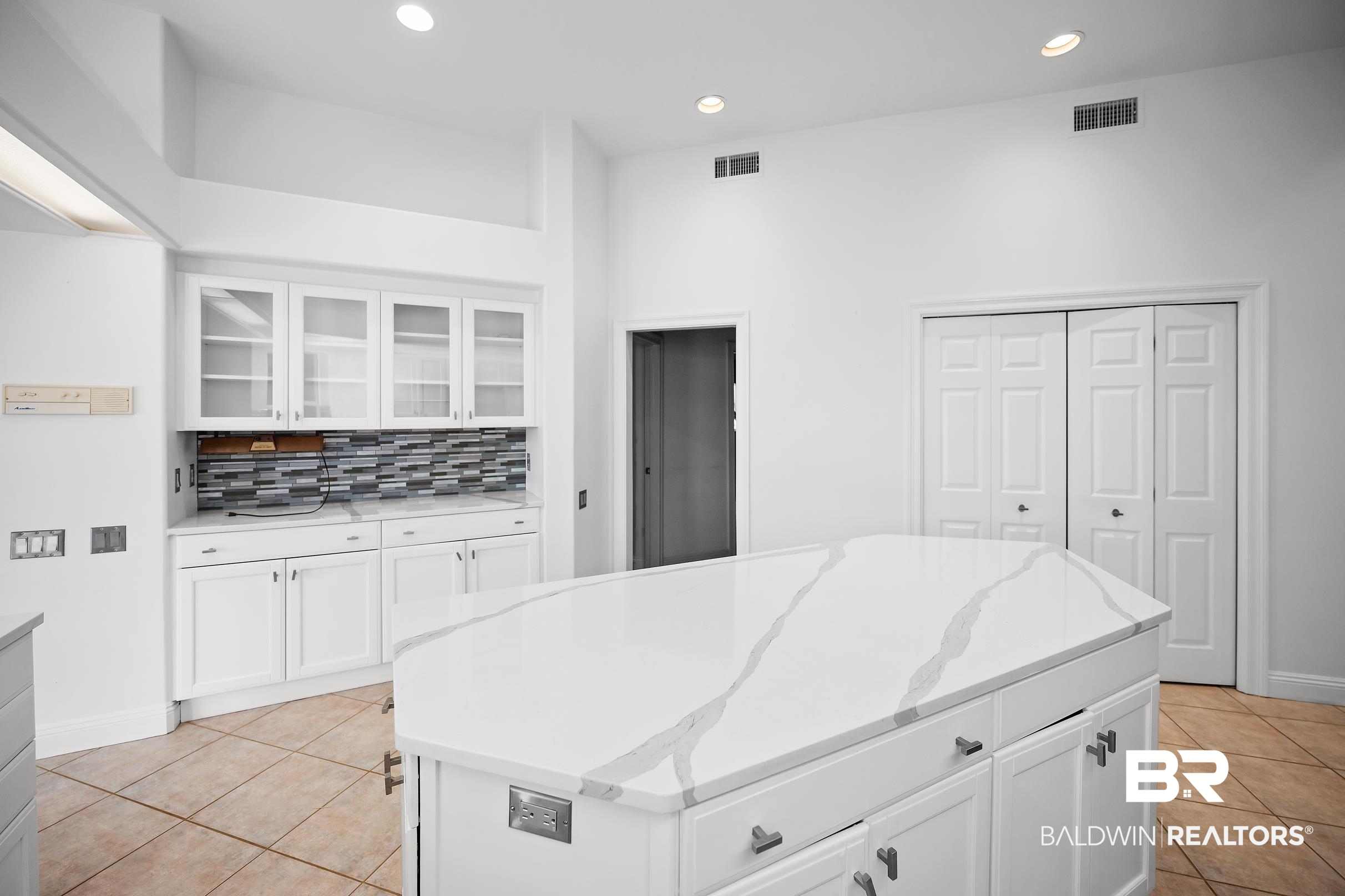 8591 Bay Harbor Road Elberta, AL 36530 - Photo 21 of 56 Kitchen with white cabinets, glass insert cabinets, light stone counters, a center island, and recessed lighting