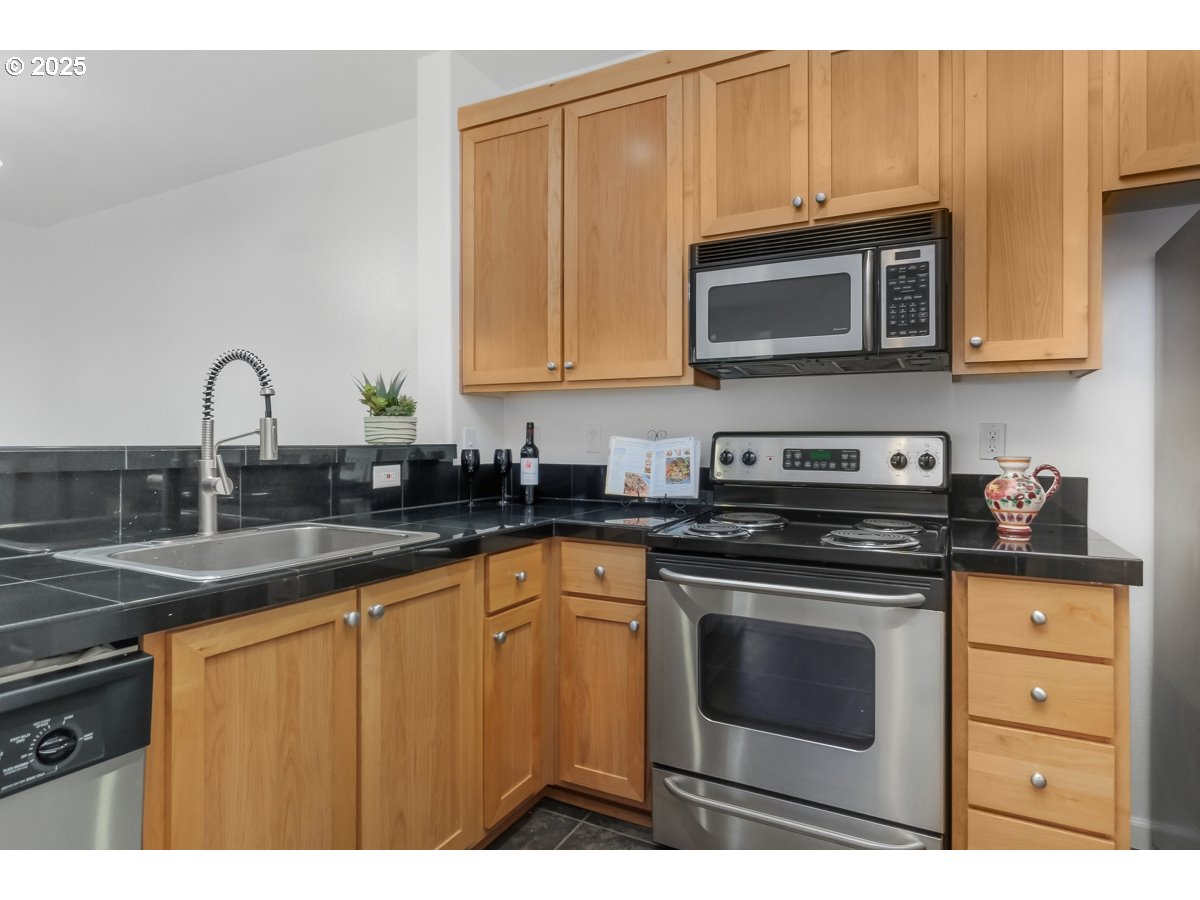 1180 Southwest 170th Avenue, Unit 100 Beaverton, OR 97003 - Photo 15 of 32 a kitchen with stainless steel appliances granite countertop a sink stove and microwave