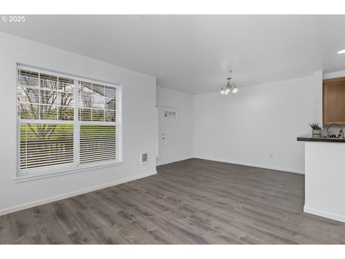 1180 Southwest 170th Avenue, Unit 100 Beaverton, OR 97003 - Photo 9 of 32 a view of an empty room with a window and wooden floor