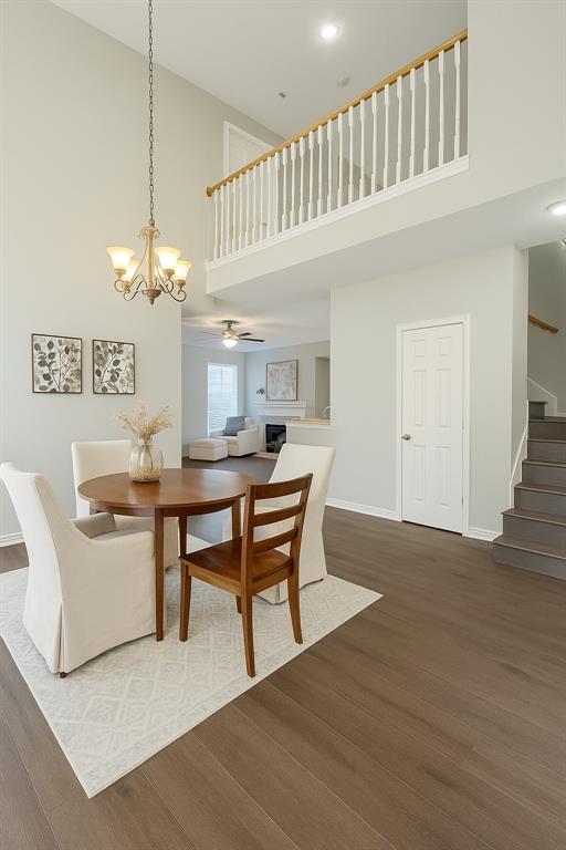 8557 Brittania Way Dallas, TX 75243 - Photo 3 of 18 Dining room featuring a high ceiling, stairway, dark wood-type flooring, a fireplace, and a chandelier