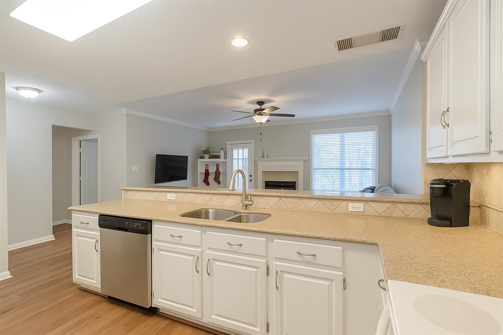 8557 Brittania Way Dallas, TX 75243 - Photo 18 of 18 Kitchen with white cabinets, open floor plan, stainless steel dishwasher, backsplash, and ornamental molding