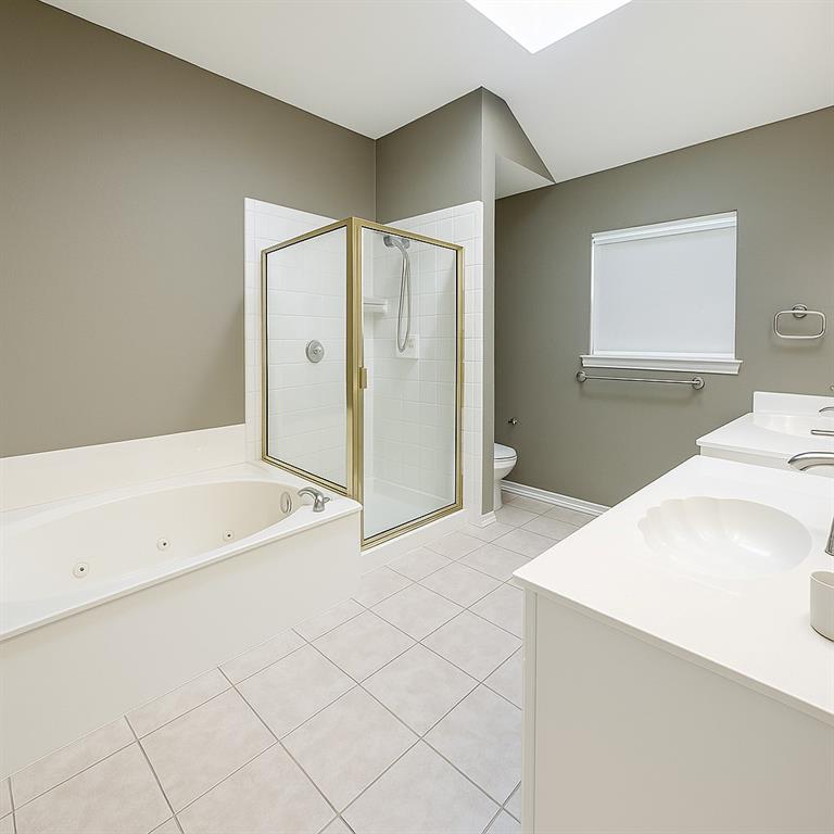 8557 Brittania Way Dallas, TX 75243 - Photo 8 of 18 Bathroom featuring light tile patterned floors, double vanity, a stall shower, and a whirlpool tub